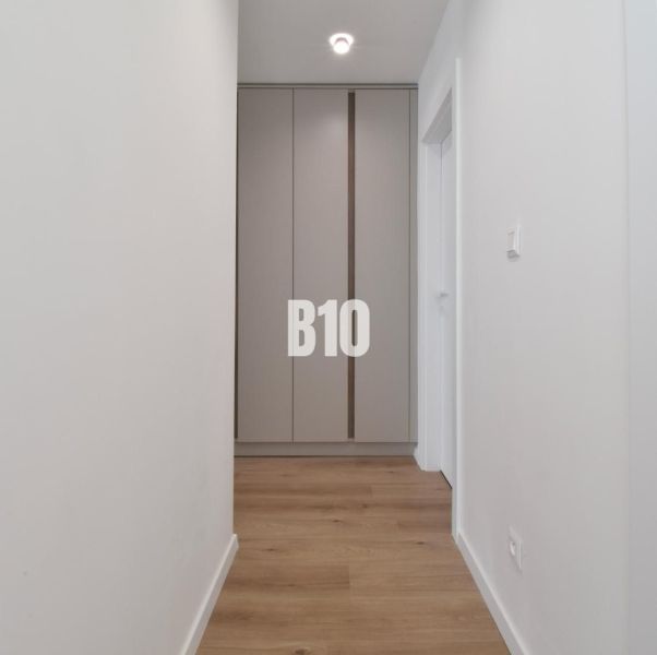 Flur mit Einbauschrank und Boden mit Holzdekor in einer 4-Zimmer-Wohnung.
