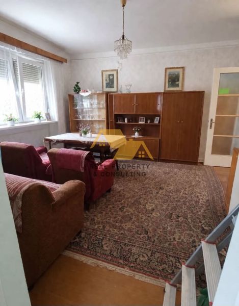 Wohnzimmer in einem Einfamilienhaus mit einer Sitzgarnitur, einem Schrank und einem Kronleuchter, Boden mit Holzdekor.