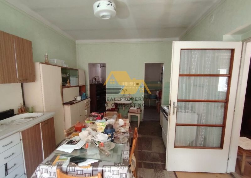 Eine Küche in einem Einfamilienhaus mit einfacher Einrichtung und einem Esstisch, Boden mit Holzdekor.