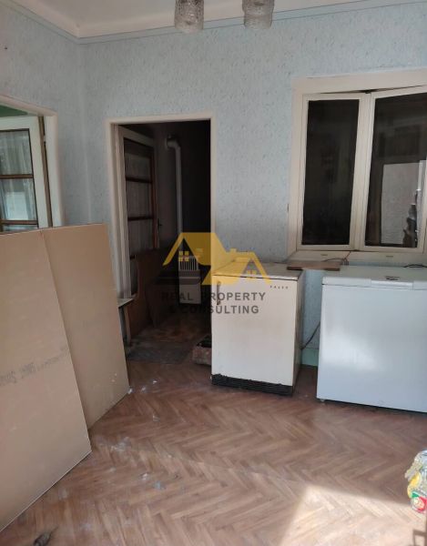 Ein Zimmer in einem Einfamilienhaus mit einem Holzboden und älteren Möbeln.