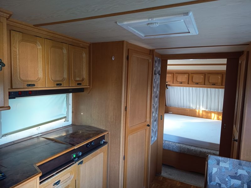 Das Innere eines Wohnmobils mit Küche und Schlafzimmer, Holzboden, Gärten.