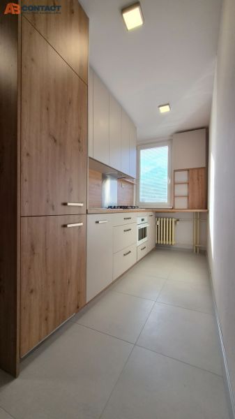 Küche in einer Einzimmerwohnung mit Holzdekor und eingebauten Geräten.
