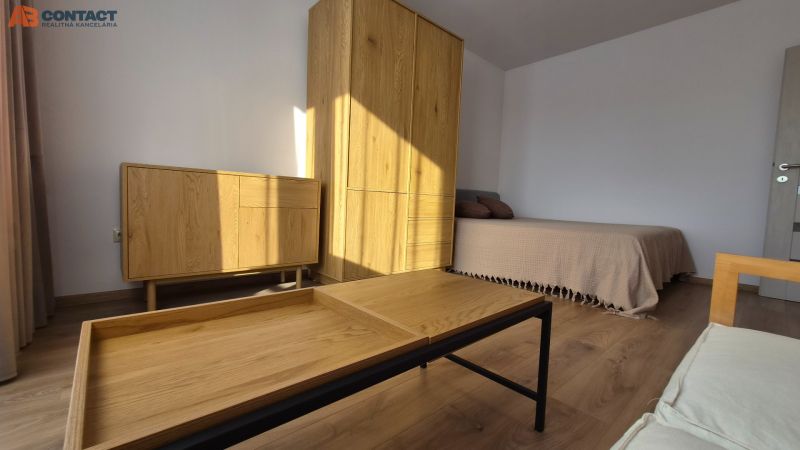 Innenraum einer Einzimmerwohnung mit Bett, Holzmöbeln und Boden mit Holzdekor.