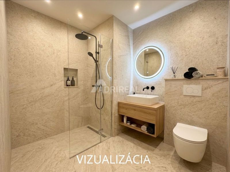 Badezimmer in einer Einzimmerwohnung mit verglaster Duschkabine und beleuchtetem Spiegel.