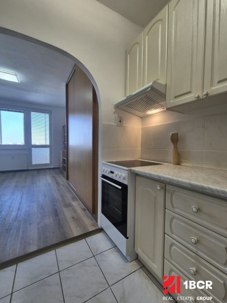 Kochnische in einem Einzimmerapartment mit Holzboden und Fliesen.