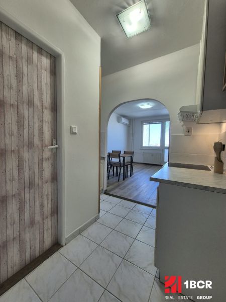 Einzimmerwohnung mit Küche und Holzboden, die zum Esszimmer führt.