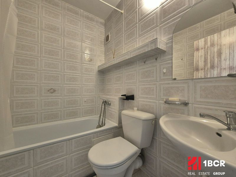 Badezimmer in einem Studio-Apartment mit Badewanne, Waschbecken und Toilette in gedämpften Farben.