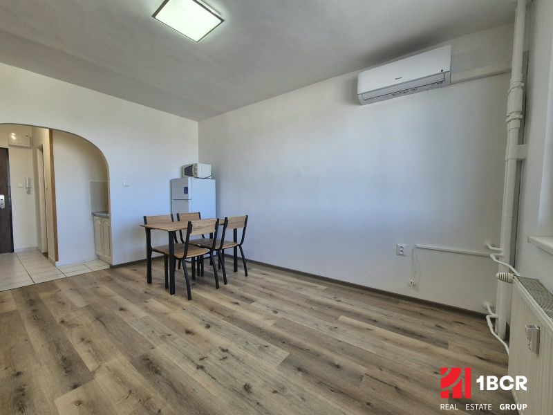 Einzimmerwohnung mit Holzboden, Esstisch, Klimaanlage, einfache Einrichtung.