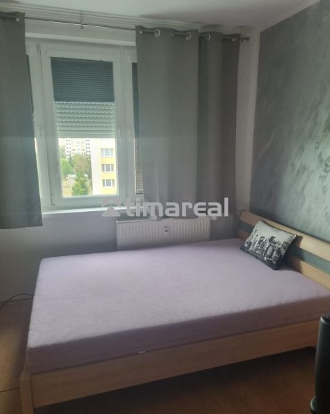 Schlafzimmer in einer 3-Zimmer-Wohnung mit Bett und grauem Dekokissen.