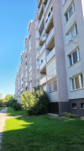 Außenbereich eines Plattenbaus in Trnava mit Grünflächen und einem Gehweg zu einer 3-Zimmer-Wohnung.