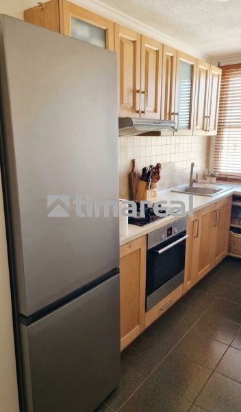 Küchenzeile in einer 3-Zimmer-Wohnung mit Holzschränken und Geräten.