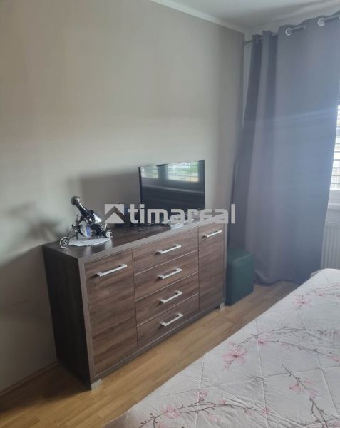 Innenraum einer 3-Zimmer-Wohnung mit Kommode und Fernseher, Boden mit Holzdekor.