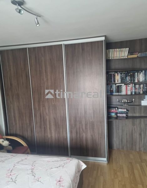Ein Schrank und ein Bücherregal in einer 3-Zimmer-Wohnung, mit einem Boden in Holzoptik.