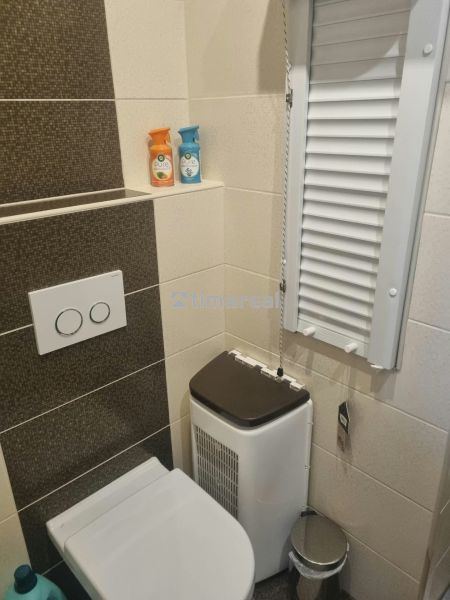 Badezimmer mit Toilette in einer 3-Zimmer-Wohnung, creme-braune Fliesen und Stauraum.