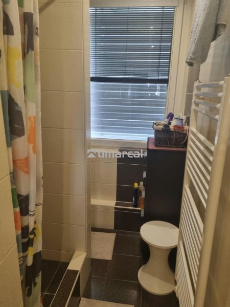 Badezimmer mit gefliester Dusche, Vorhang und Fenster in einer 3-Zimmer-Wohnung.