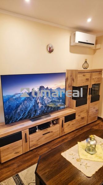 Wohnzimmer mit Fernseher, dekorativen Möbeln und Holzboden in einer 3-Zimmer-Wohnung.