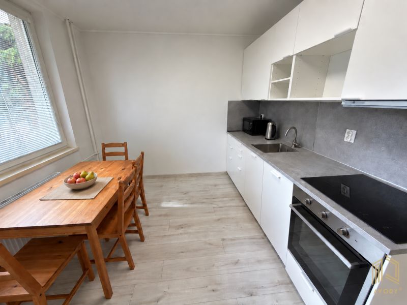 Küche in einer 2-Zimmer-Wohnung mit weißer Küchenzeile und Boden in Holzoptik.