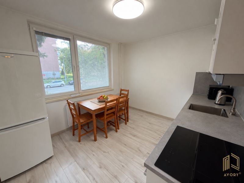 Küche in einer 2-Zimmer-Wohnung mit Holzboden, Esstisch und Geräten.