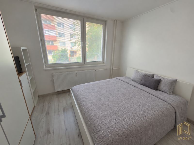 Helles Schlafzimmer in einer 2-Zimmer-Wohnung mit großem Fenster und Bett.
