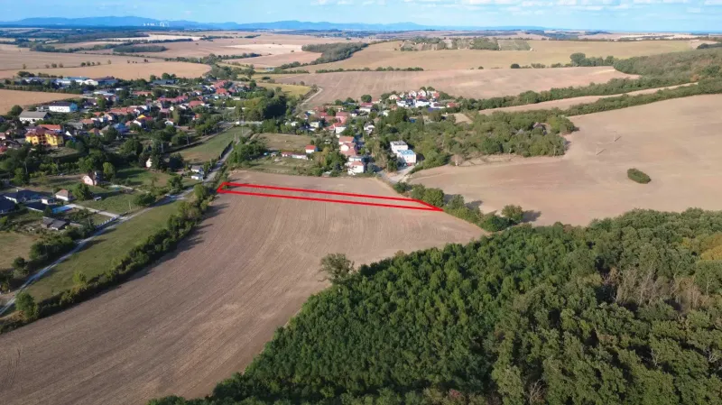 Luftaufnahme von landwirtschaftlichen und forstwirtschaftlichen Flächen in Podhájska, umgeben von einem Dorf und Natur.