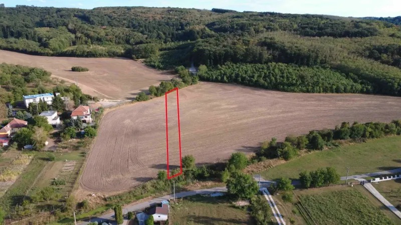 Ländliche Aussicht auf landwirtschaftliche und forstwirtschaftliche Flächen in Podhájska, die eine Siedlung mit Einfamilienhäusern umgeben.