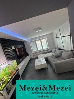 Wohnzimmer einer Zweizimmerwohnung mit Holzboden, Sofa und Aquarium.