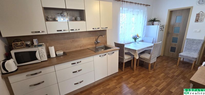 Küche im Einfamilienhaus mit weißen Schränken und einem Boden in Holzoptik.