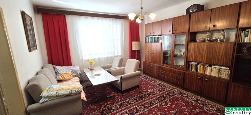 Wohnzimmer in einem Einfamilienhaus mit bequemen Sofas, einem Holzschrank und einem roten Teppich.