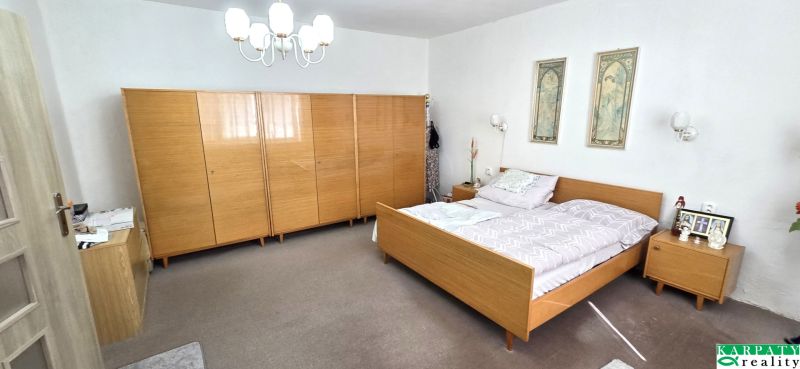 Schlafzimmer in einem Einfamilienhaus mit Holzmöbeln, Teppichboden und Wanddekorationen.