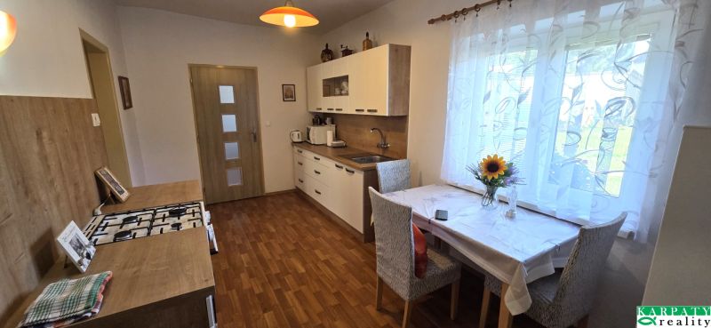 Küche in einem Einfamilienhaus mit Holzboden und Blumen auf dem Tisch.