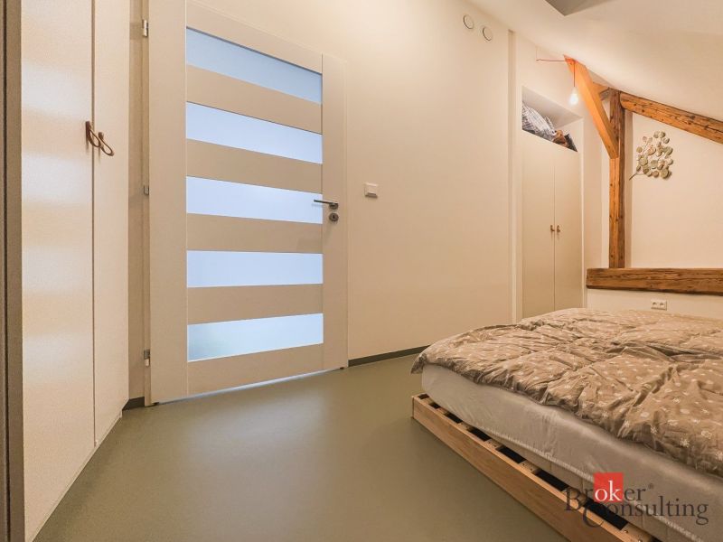 Schlafzimmer mit Holzelementen, einem Bett aus Paletten und Stauraum in einer 3-Zimmer-Wohnung.