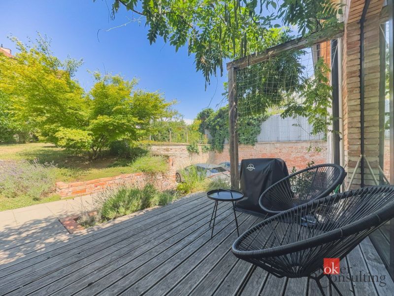 Terrasse in einer 3-Zimmer-Wohnung mit Holzelementen, Garten und Außenbereich zum Sitzen.