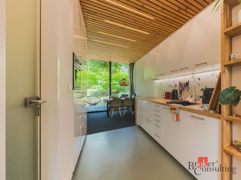Küche in einer 3-Zimmer-Wohnung mit Holzbalkendecke und großen verglasten Fenstern.