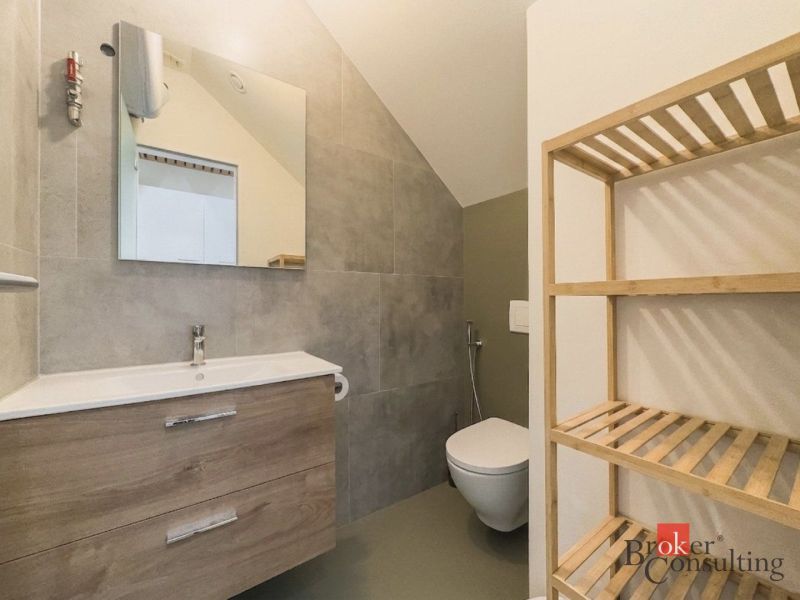 Badezimmer in einer 3-Zimmer-Wohnung mit Waschbecken, Holzregal und Spiegel an der Wand.