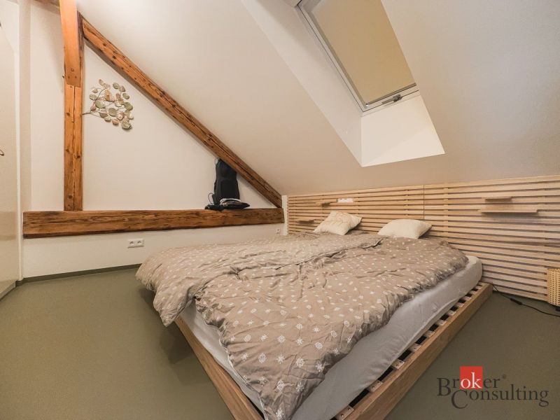 Ein Schlafzimmer im Dachgeschoss mit Holzelementen und einem Doppelbett in einer 3-Zimmer-Wohnung.