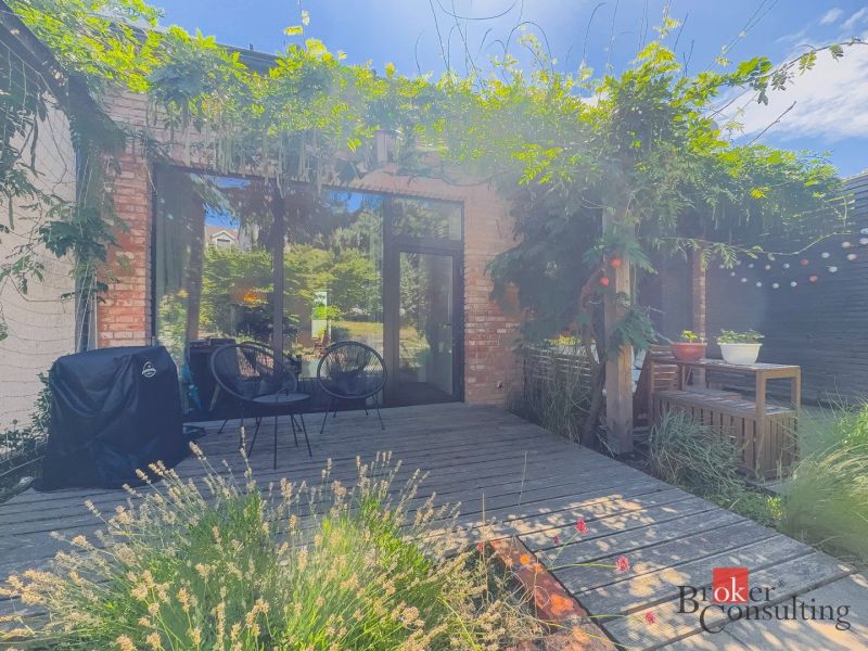 Terrasse mit Grün, Holzelementen und Sitzgelegenheiten im Garten einer 3-Zimmer-Wohnung.