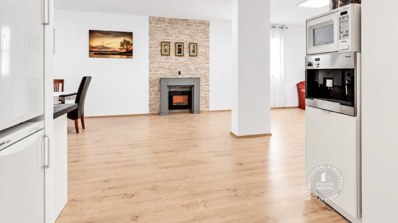 Innenraum einer 2-Zimmer-Wohnung mit Kamin und Holzboden, wo auch die Kochnische zu sehen ist.