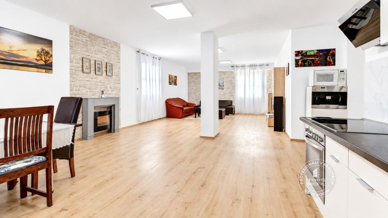 Geräumiges Wohnzimmer in einer 2-Zimmer-Wohnung mit Holzboden und Kamin.