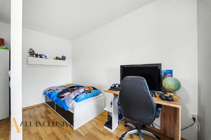 Kinderzimmer in einem Einfamilienhaus mit Bett, Tisch und Boden in Holzoptik.