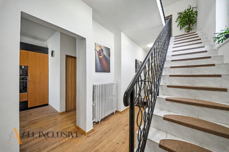Eine Treppe mit weißen Stufen und einem Boden in Holzoptik in einem Einfamilienhaus.