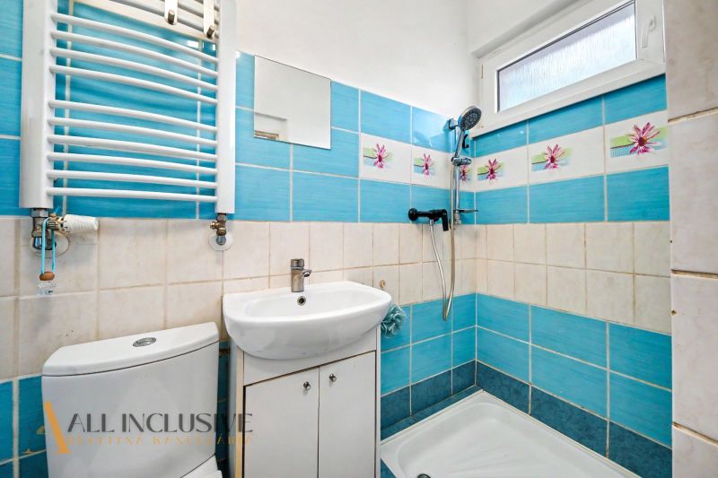 Ein Badezimmer in einem Einfamilienhaus mit blauen Fliesen und weißer Ausstattung.