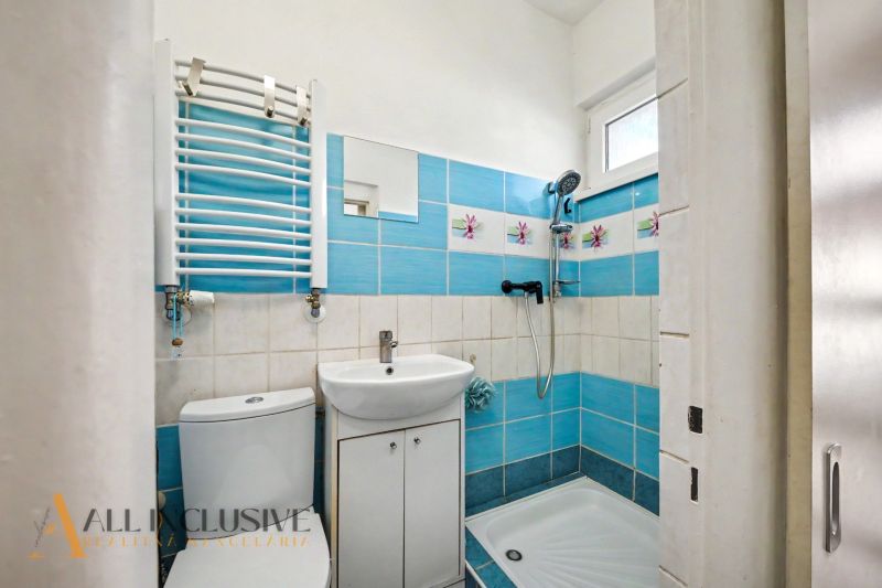 Ein Badezimmer in einem Einfamilienhaus mit weißer Sanitärausstattung und blauen Fliesen.