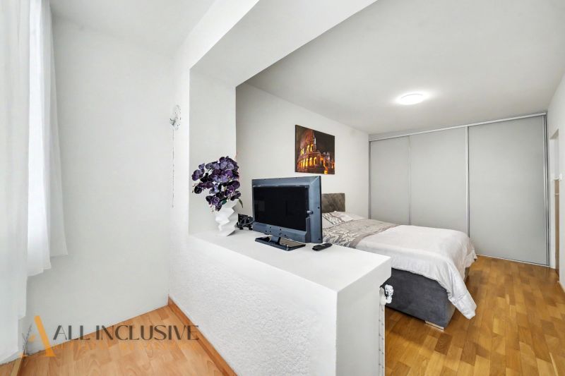 Helles Schlafzimmer mit Fernseher, Bett und Holzboden in einem Einfamilienhaus.