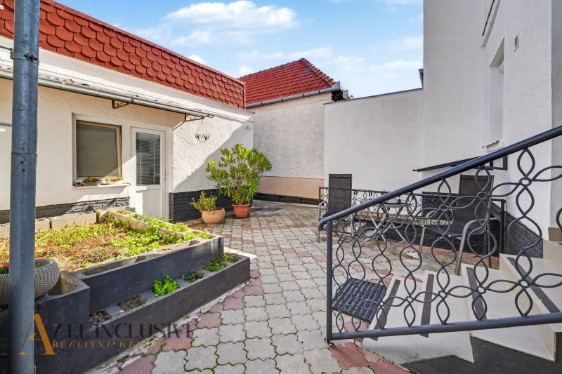 Der Hof eines Einfamilienhauses in Trstice mit einer Terrasse und Blumenbeeten in Pflanzgefäßen.
