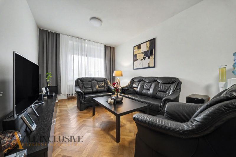 Wohnzimmer in einem Einfamilienhaus mit schwarzen Ledermöbeln und einem Fernseher.