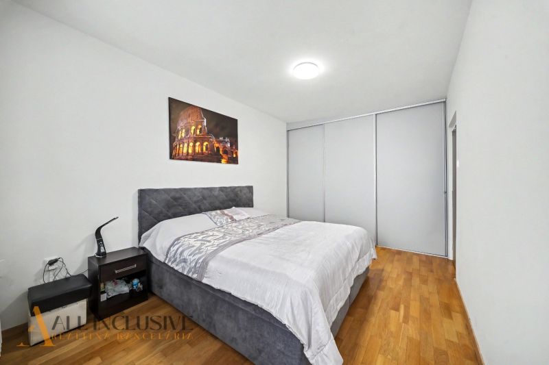 Schlafzimmer mit großem Bett, Nachttisch und Boden mit Holzdekor in einem Einfamilienhaus.