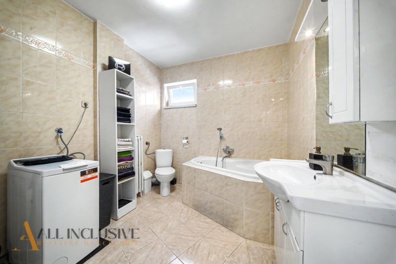Ein Badezimmer in einem Einfamilienhaus mit einer Badewanne, einem Waschbecken, einer Waschmaschine und einem Regalschrank.