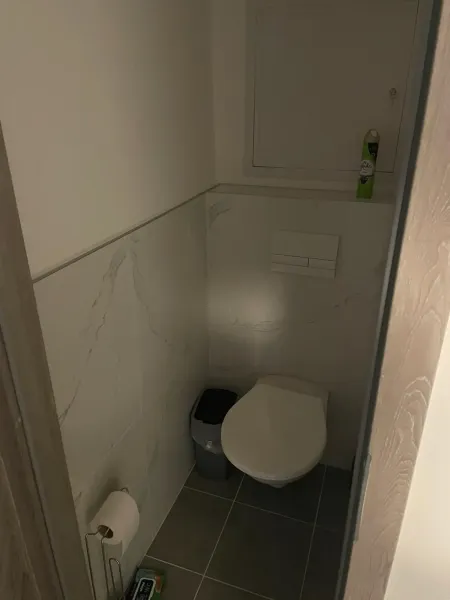 Toilette mit Fliesen und Lufterfrischer in einer 2-Zimmer-Wohnung.