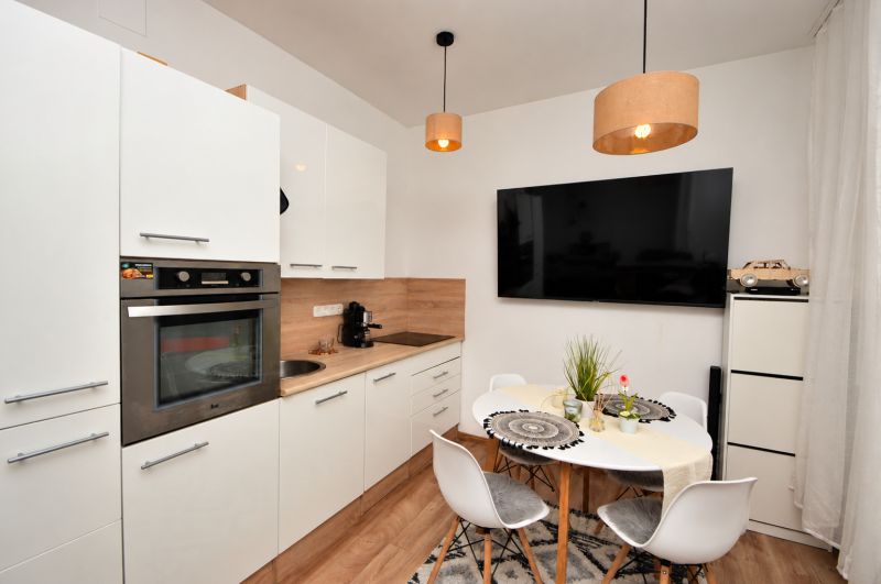 Kompakte Küche in einer Einzimmerwohnung mit Holzboden und Essecke.