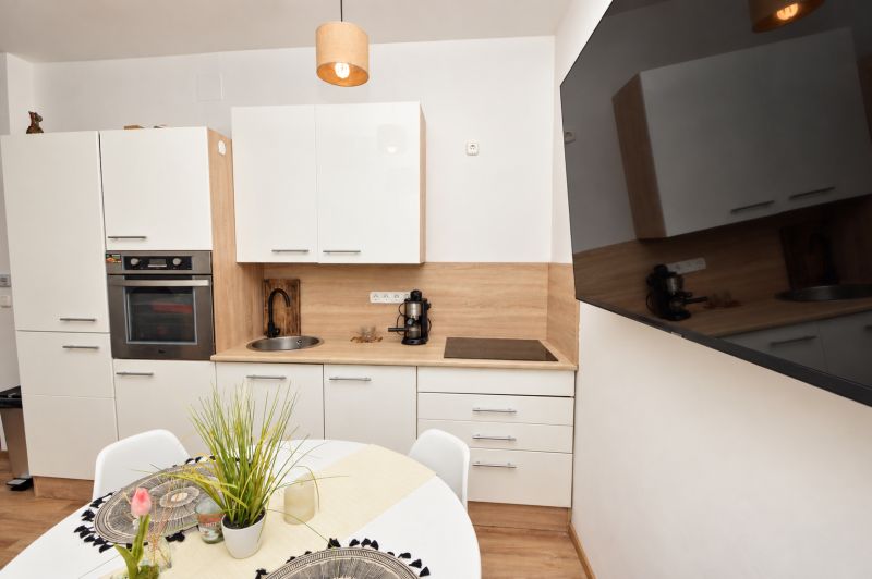 Küchenzeile in einer Einzimmerwohnung mit weißen Schränken und einem Boden in Holzoptik.